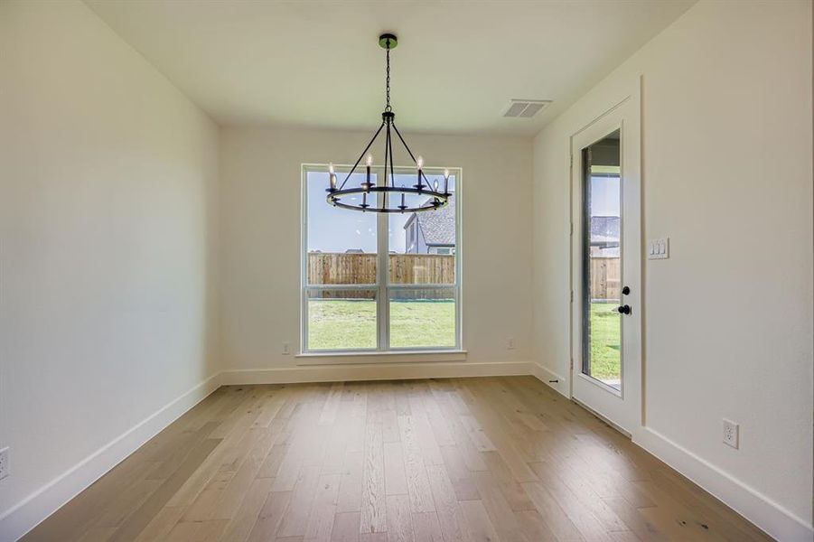 Unfurnished dining area featuring a chandelier and light wood finished floors