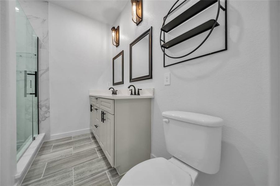 Bathroom with vanity, toilet, and a shower with shower door