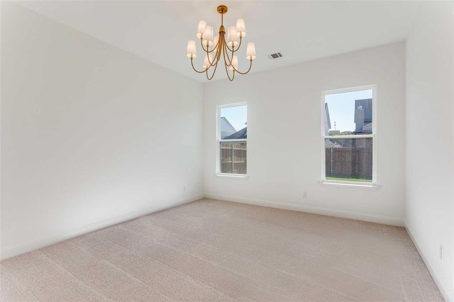 Carpeted spare room featuring an inviting chandelier