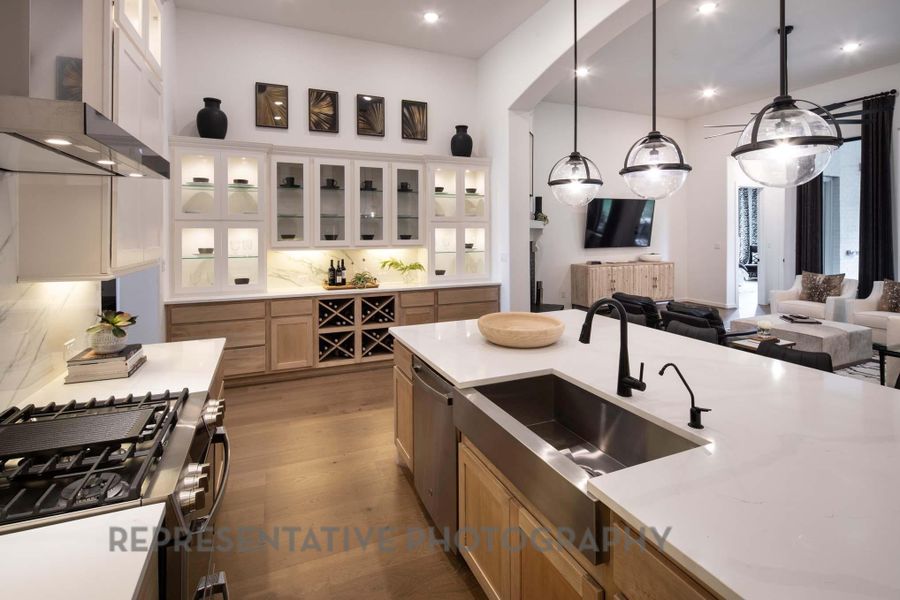 Kitchen featuring stainless steel appliances, wall chimney exhaust hood, a sink, decorative backsplash, and wood finished floors Kitchen featuring stainless steel appliances, wall chimney exhaust hood, a sink, decorative backsplash, and wood finished floors