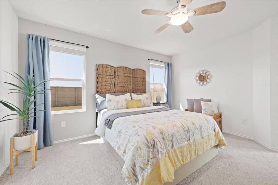 This spacious primary retreat features expansive windows and a high-quality ceiling fan, offering a tranquil sanctuary with plenty of room for a full suite of bedroom furniture.
