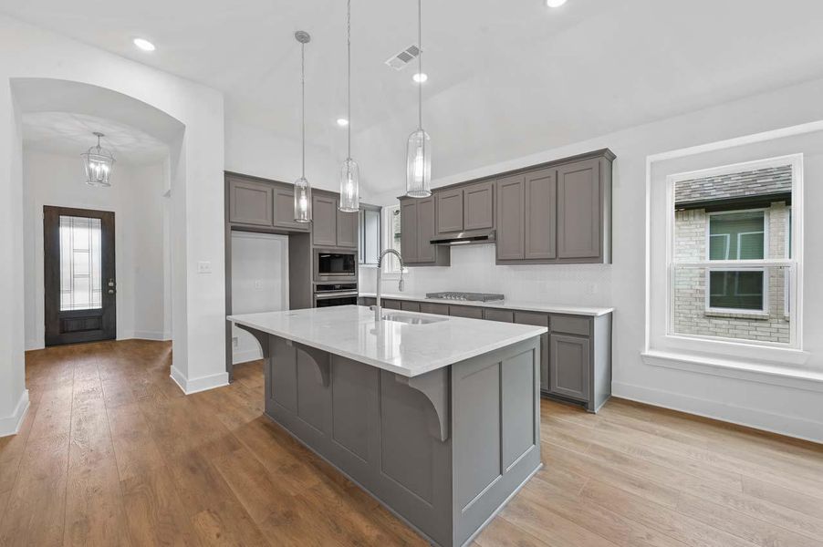 Kitchen with black cooktop, built in microwave, a sink, oven, and baseboards