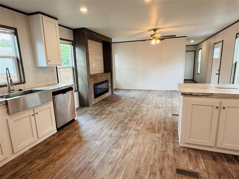 Kitchen featuring a sink, dishwasher, wood finished floors, and light countertops