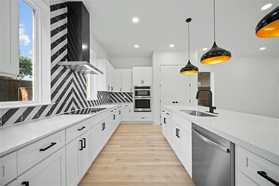 Kitchen with stainless steel appliances, decorative backsplash, wall chimney exhaust hood, white cabinetry, and light wood-style flooring