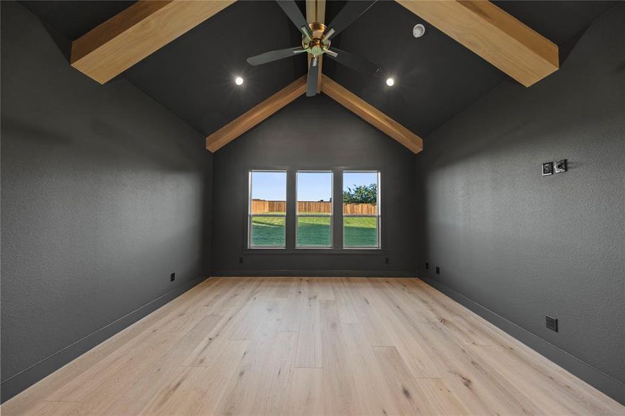 Vaulted ceiling with exposed wood beams and a ceiling fan