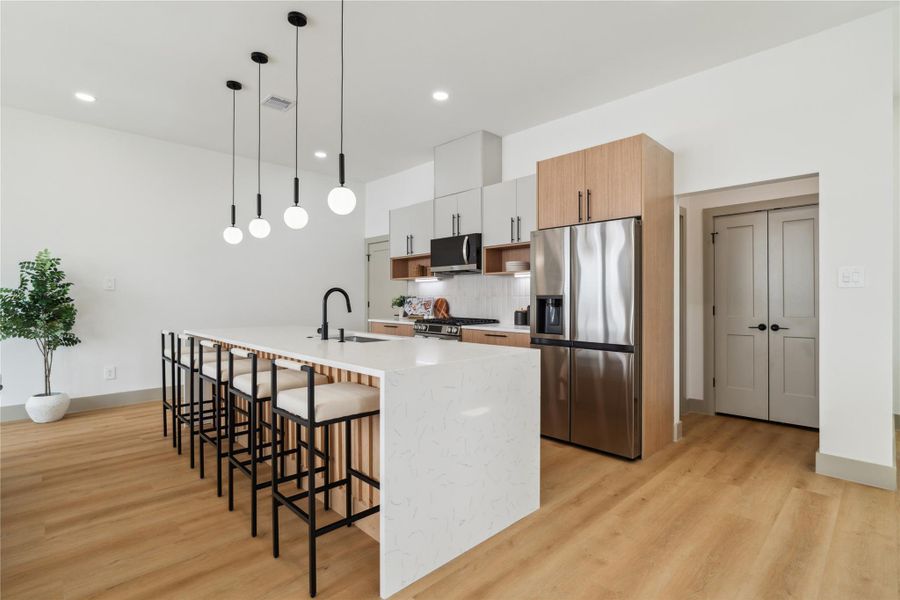 A showcase of refined craftsmanship, the waterfall-edge island features soft veining and fluted wood accents, balancing elegance with texture.