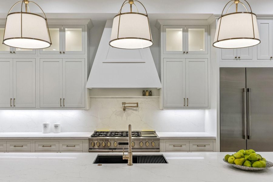 A closer view of this gorgeous kitchen showcases Slab Quartz Counter and Backsplash, 33 Inch Undermount Single Basin Sink in Quartz Composite Finish, Pull-Down Faucet and a Top Switch Disposal, 24“ Pot Filler in a Champagne Bronze Finish and LED Under-Cabinet Lighting and Under-Cabinet PlugMold. Inset Cabinetry and Lighting on the Upper Cabinets. A closer view of this gorgeous kitchen showcases Slab Quartz Counter and Backsplash, 33 Inch Undermount Single Basin Sink in Quartz Composite Finish, Pull-Down Faucet and a Top Switch Disposal, 24“ Pot Filler in a Champagne Bronze Finish and LED Under-Cabinet Lighting and Under-Cabinet PlugMold. Inset Cabinetry and Lighting on the Upper Cabinets.
