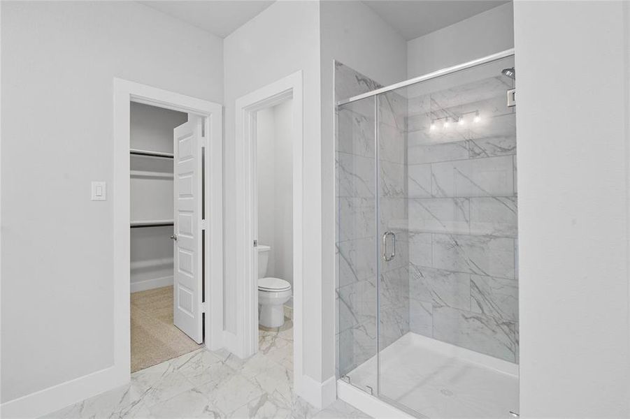 This additional view of the primary bath showcased the large walk-in shower with tile surround, privacy toilet area, and spacious walk-in closet.