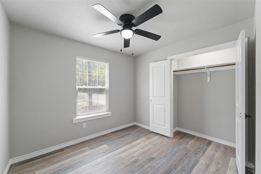 Room featuring wood-finish flooring, light grey wall paint, and white baseboards Room featuring wood-finish flooring, light grey wall paint, and white baseboards