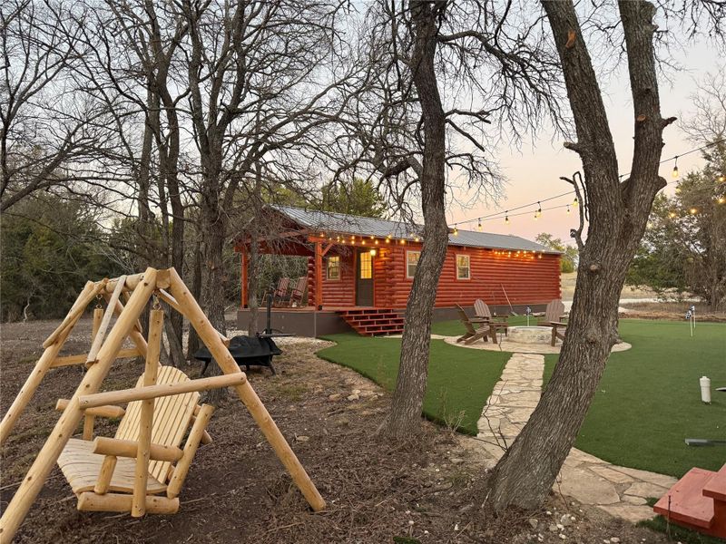 View outdoor fire pit, a patio area, a wooden deck, and a putting area