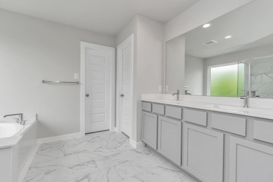 Elevate your daily routine at the elegant vanity, now equipped with double sinks, light countertops, modern hardware, and beautiful recessed lights. Sample photo of completed home with similar floor plan. Actual colors and selections may vary.