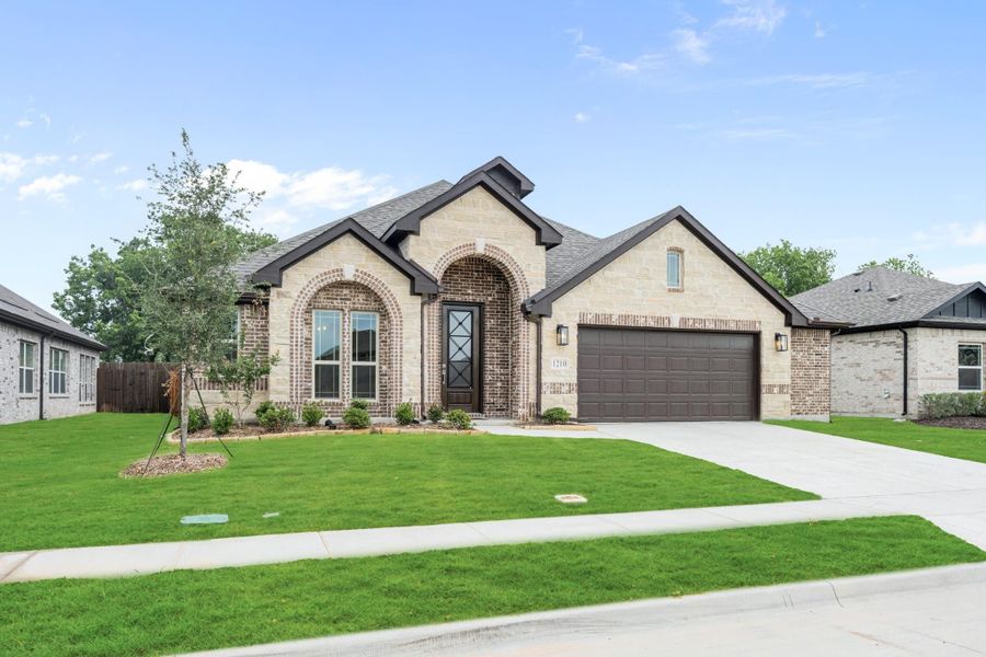 Single-story home with brick and stone exterior, arched entry, two-car garage, and green front lawn