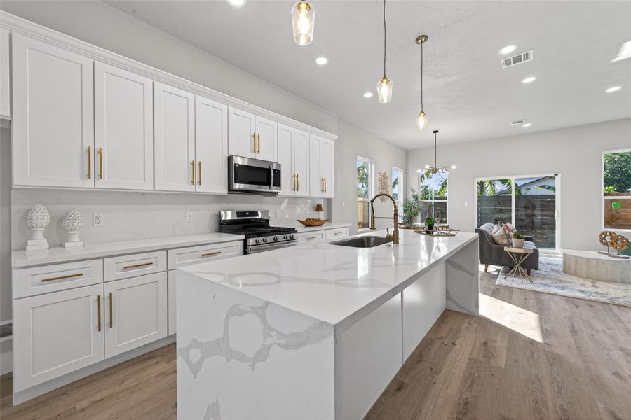 Open sightline from kitchen to dining and living areas, enhanced by designer pendant lighting, recessed LEDs, and abundant natural light—perfect for hosting or relaxed daily living.