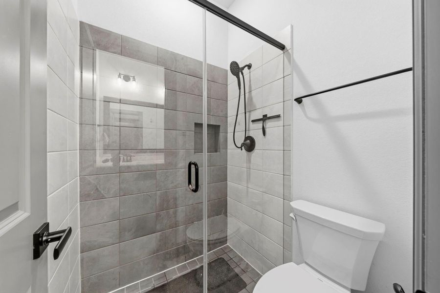 Stylish walk-in shower with frameless glass enclosure, modern tile finishes, and built-in niche for added convenience.