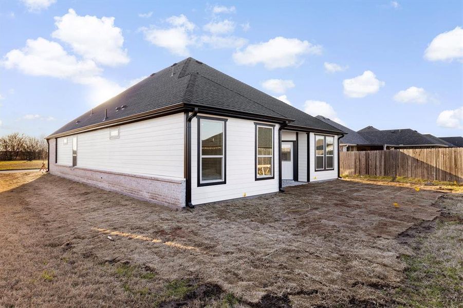 Back of property with brick siding, a shingled roof, and fence Back of property with brick siding, a shingled roof, and fence