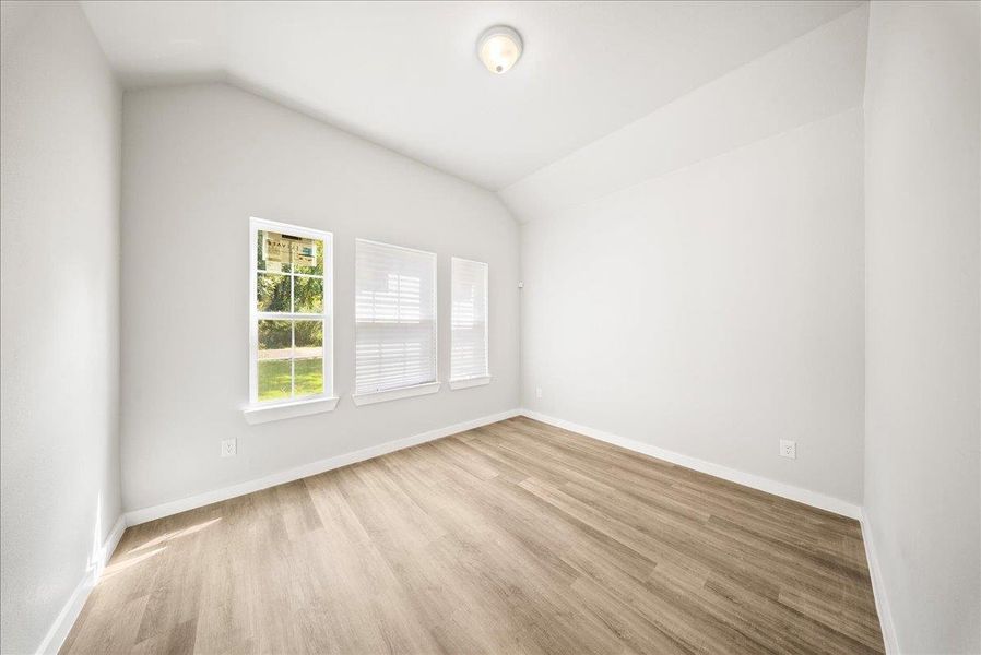 Spare room with vaulted ceiling and light wood finished floors Spare room with vaulted ceiling and light wood finished floors