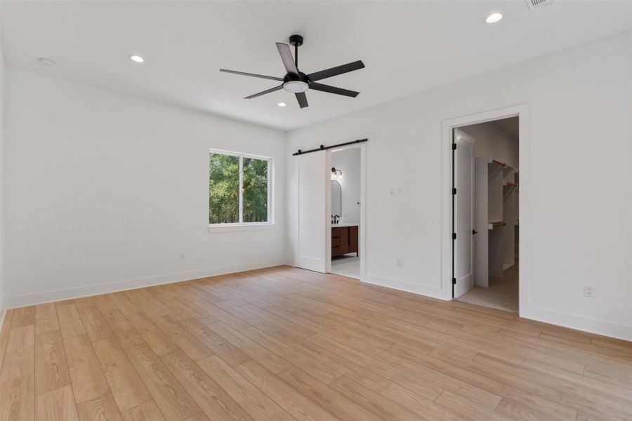 A well-lit bedroom features hardwood flooring and a contemporary ceiling fan, offering a tranquil retreat.