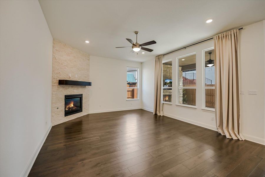 Unfurnished living room with a stone fireplace, dark wood-type flooring, a ceiling fan, and recessed lighting Unfurnished living room with a stone fireplace, dark wood-type flooring, a ceiling fan, and recessed lighting