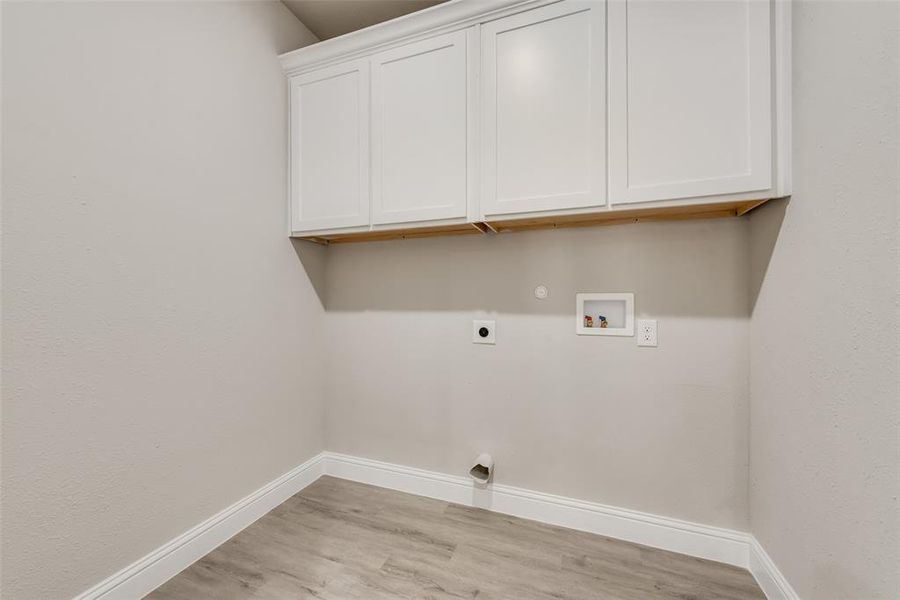 Washroom featuring washer hookup, light wood-type flooring, electric dryer hookup, cabinets, and gas dryer hookup