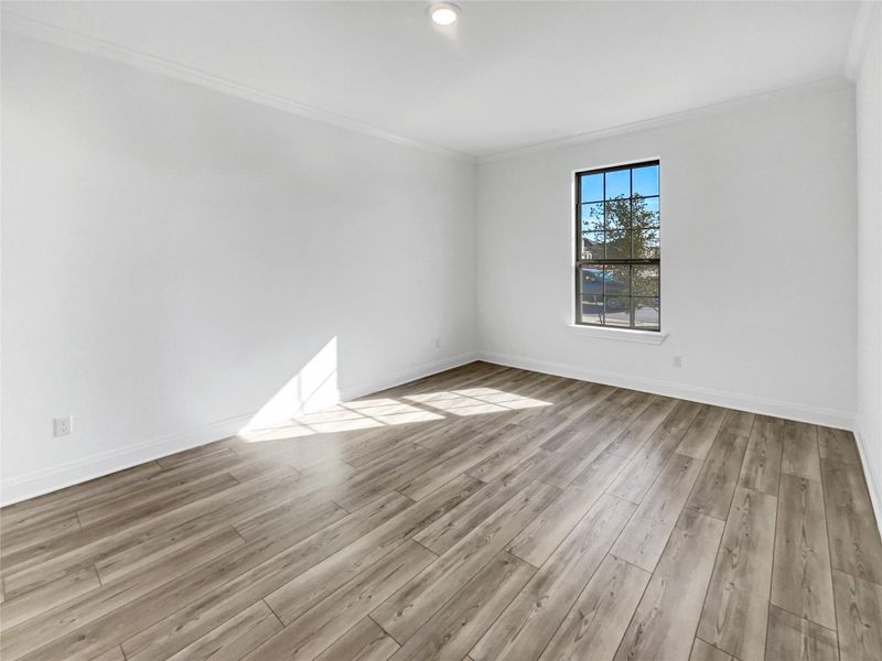 Unfurnished room featuring crown molding, wood finished floors, and baseboards