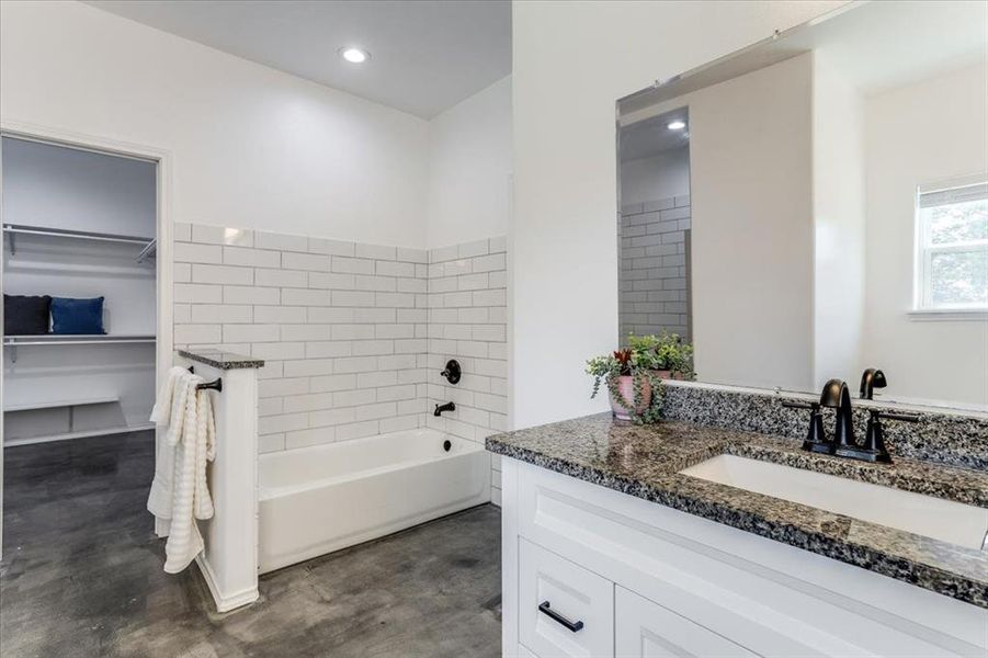 Bathroom vanity with a granite countertop, undermount sink, and matte black faucet