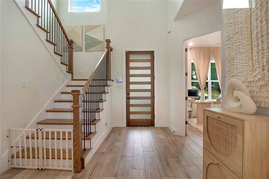 Foyer entrance featuring light wood-type flooring and a high ceiling Foyer entrance featuring light wood-type flooring and a high ceiling