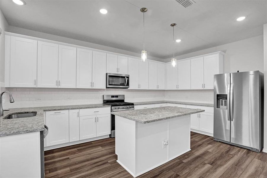 Modern kitchen featuring white shaker cabinetry, stainless steel appliances, a center island with counter seating, granite countertops, and wood-finish flooring