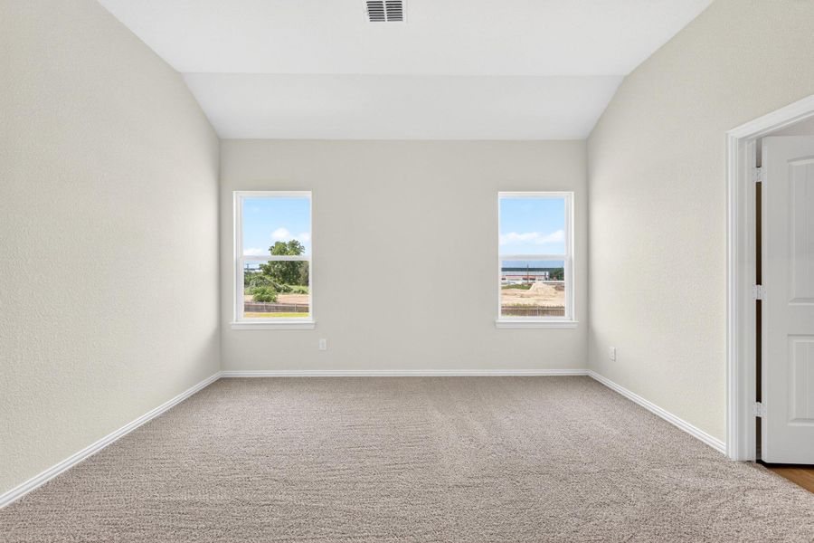 High vaulted ceilings and plush carpeting define this airy primary bedroom space.