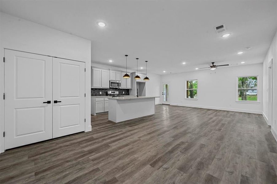 Unfurnished living room featuring dark wood-type flooring and ceiling fan