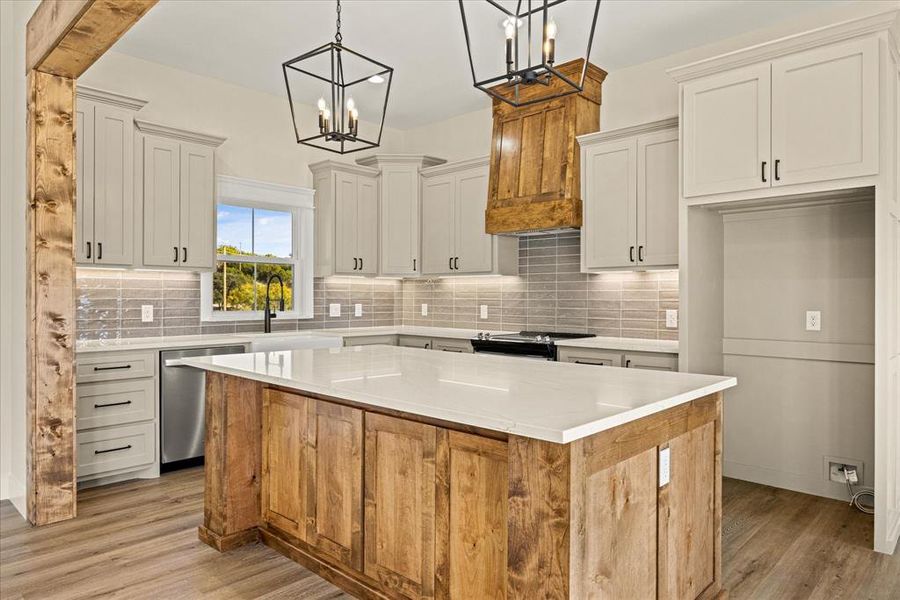 Kitchen featuring a center island, decorative light fixtures, backsplash, and light wood finished floors