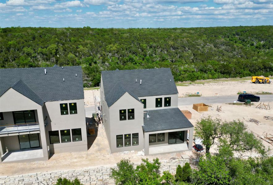 The property features a dark gray shingled roof, light-colored exterior walls, and multiple windows with dark frames