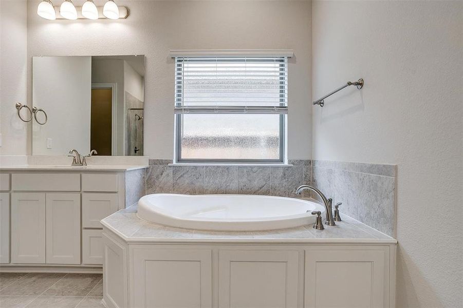 Bathroom with vanity, tile patterned flooring, and a bathtub