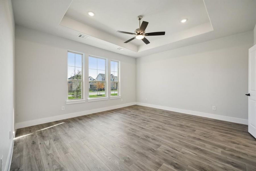 Spare room featuring a tray ceiling, ceiling fan, and hardwood / wood-style flooring