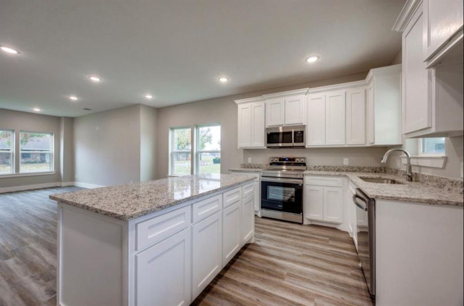 Kitchen with appliances with stainless steel finishes, white cabinetry, a center island, healthy amount of natural light, and recessed lighting