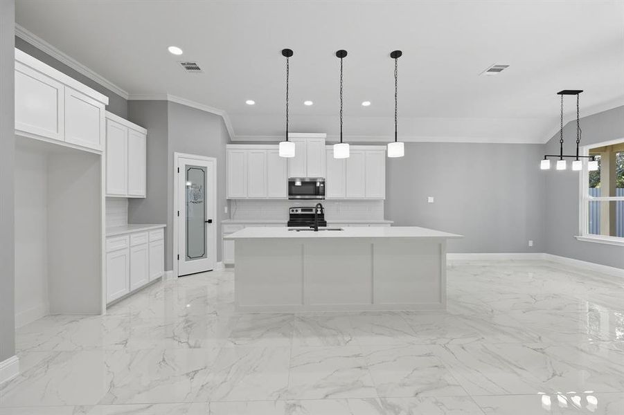 Kitchen with ornamental molding, tasteful backsplash, pendant lighting, white cabinets, and stainless steel appliances Kitchen with ornamental molding, tasteful backsplash, pendant lighting, white cabinets, and stainless steel appliances