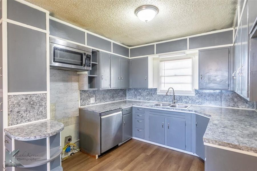 Kitchen featuring open shelves, a textured ceiling, dark wood-style flooring, appliances with stainless steel finishes, and backsplash