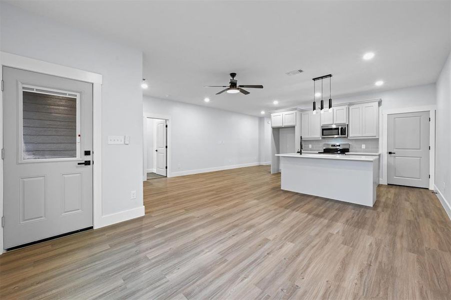 Kitchen featuring ceiling fan, white cabinetry, decorative light fixtures, a kitchen island, and appliances with stainless steel finishes