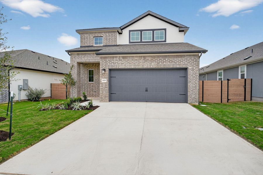 Traditional-style home featuring brick siding, concrete driveway, a garage, and a shingled roof