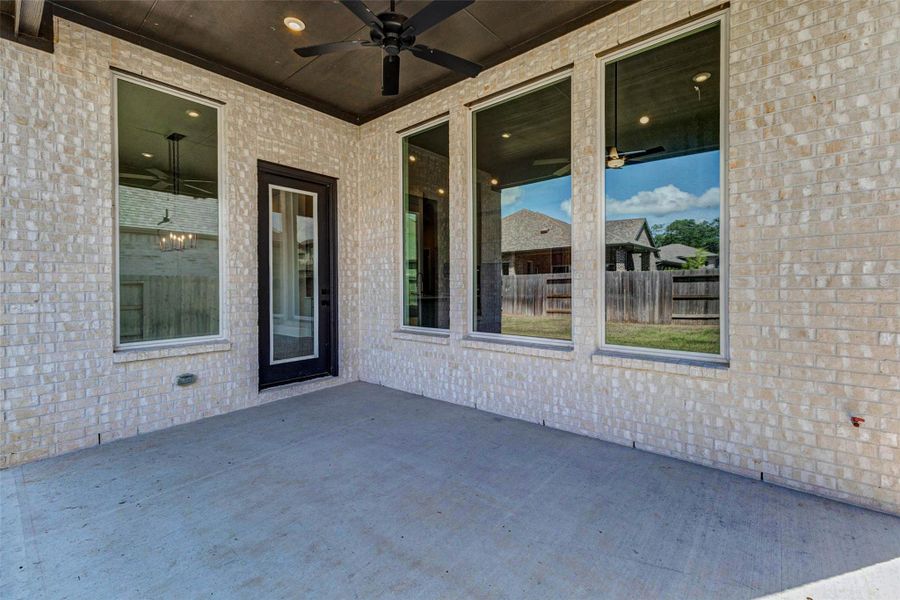 Large covered patio with a ceiling fan, providing a comfortable outdoor setting.