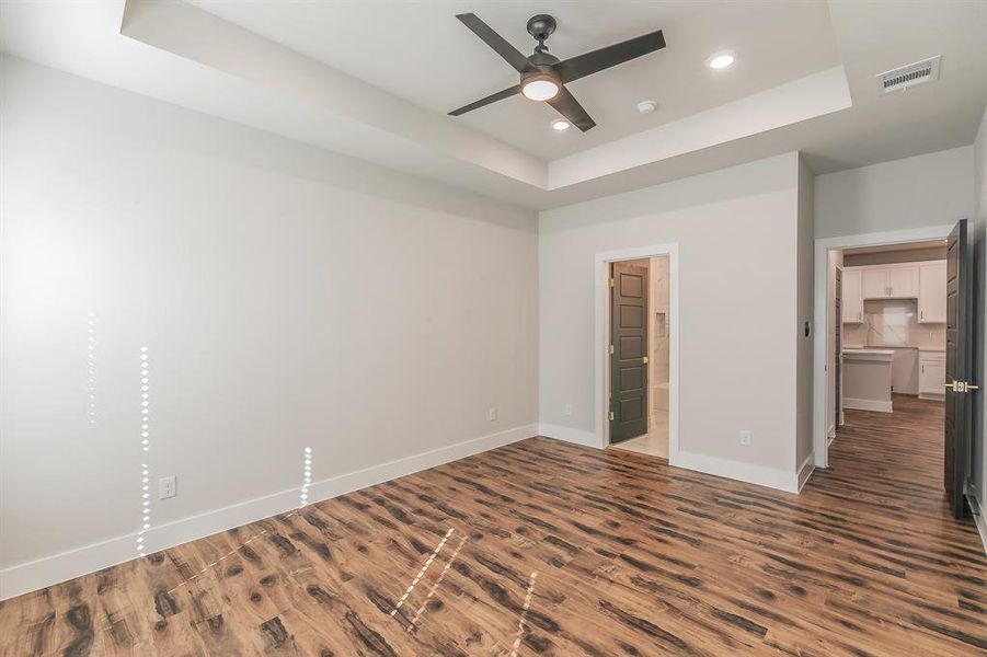 Unfurnished bedroom with dark hardwood / wood-style floors, ceiling fan, a raised ceiling, and a spacious closet