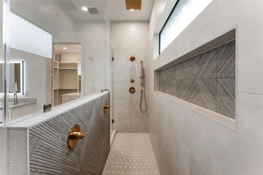 Generously sized walk-in shower features elegant design accents and integrated niches that enhance both aesthetics and functionality.