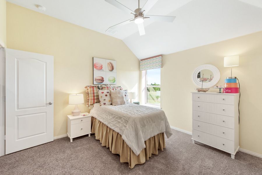 Bedroom with vaulted ceiling, ceiling fan, white dresser, and carpet flooring