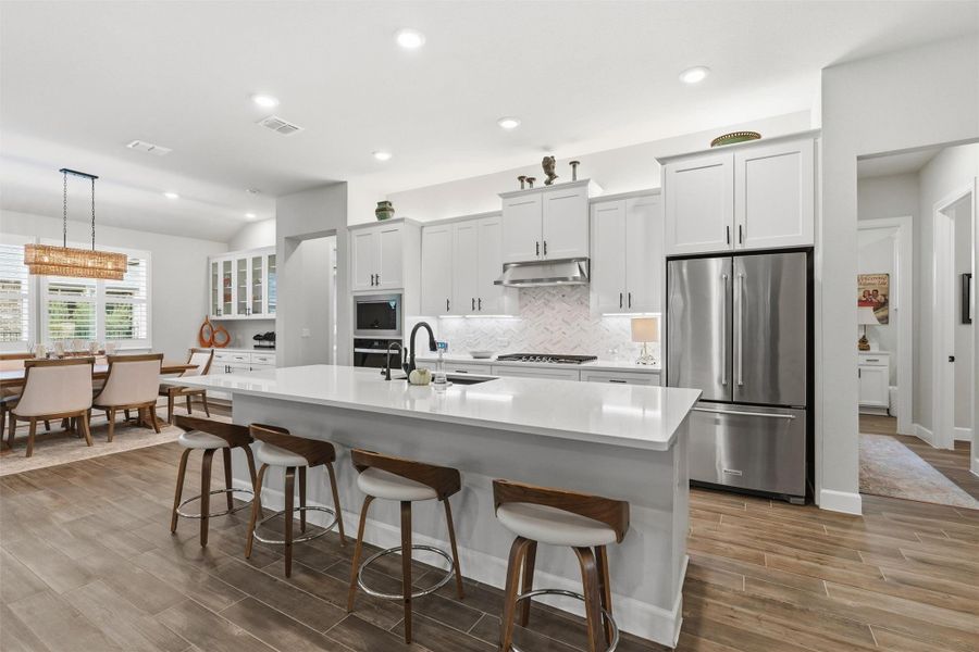 Chef's kitchen is an entertainer's dream with an extended breakfast bar with quartz counters, under-counter bar stool seating, pendant lights and a farmhouse sink. Chef's kitchen is an entertainer's dream with an extended breakfast bar with quartz counters, under-counter bar stool seating, pendant lights and a farmhouse sink.