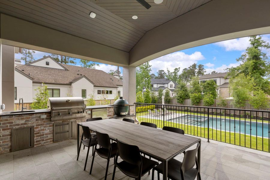 Covered outdoor living area featuring a full outdoor kitchen, built-in grill, dining space, and elevated views overlooking the pool and backyard—perfect for year-round entertaining.
