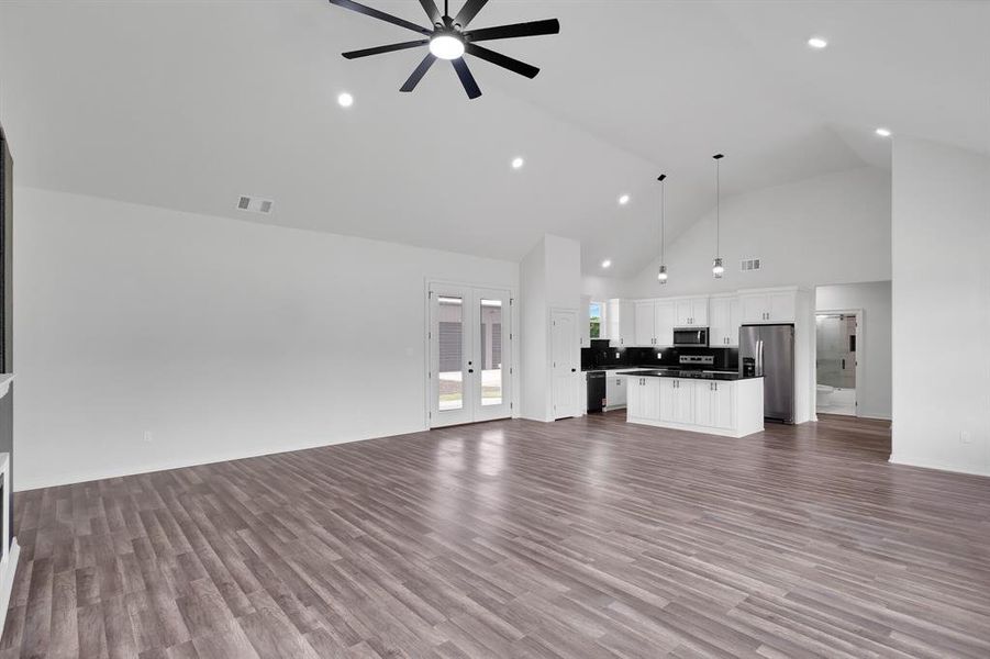 Expansive open concept living area featuring vaulted ceilings, recessed lighting, a modern ceiling fan, and durable wood-look flooring