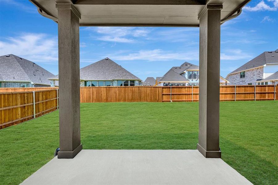 Covered patio with a concrete surface, expansive lawn, and wooden privacy fencing
