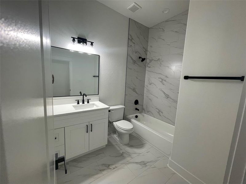 Bathroom featuring vanity, light marble finish floors, and shower / bath combination