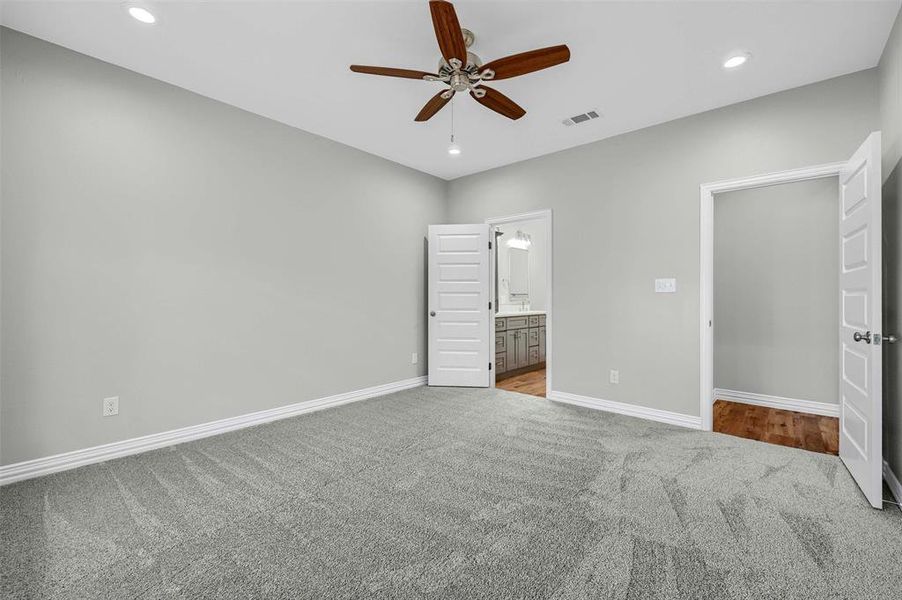 Unfurnished bedroom featuring ceiling fan, light colored carpet, and ensuite bathroom