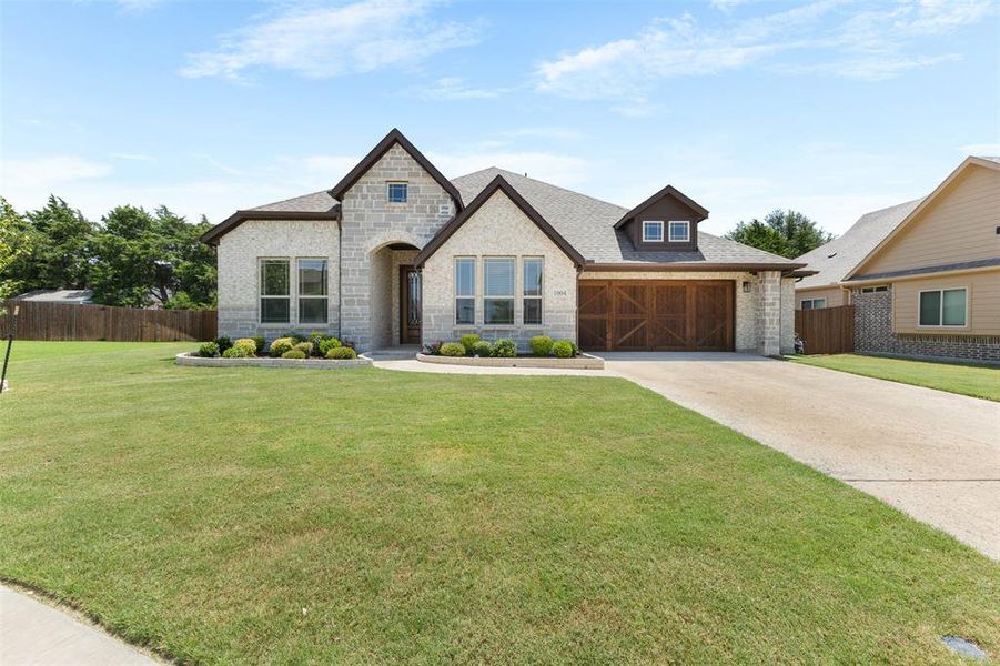Stone and brick exterior featuring a multi-gabled roofline, an arched entryway, decorative garage door, and a dormer window Stone and brick exterior featuring a multi-gabled roofline, an arched entryway, decorative garage door, and a dormer window
