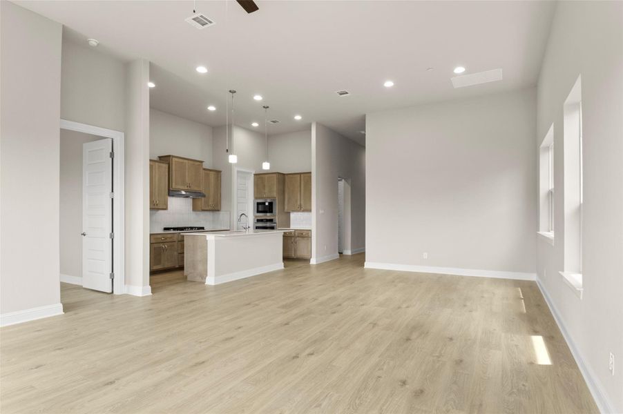 Unfurnished living room featuring a sink, recessed lighting, light wood-type flooring, ceiling fan, and baseboards